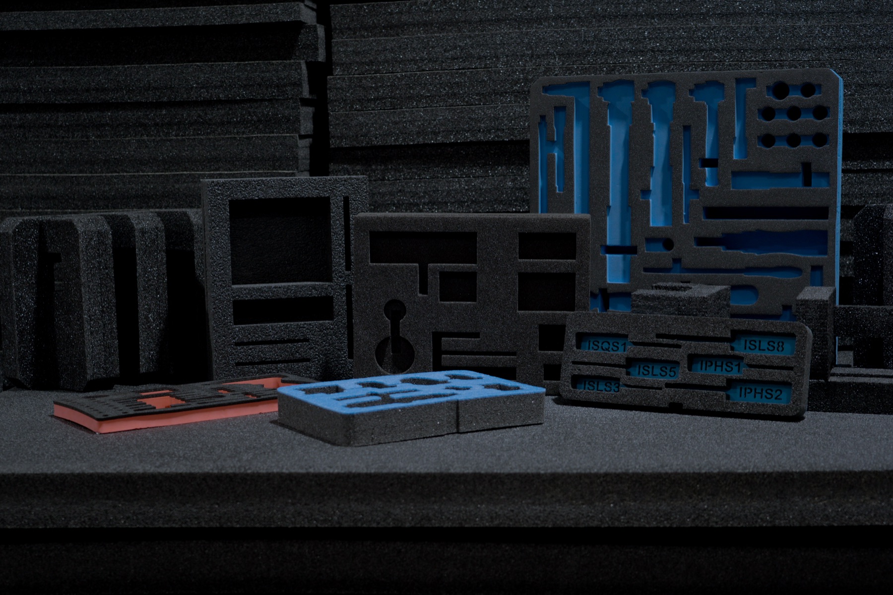 An array of custom-cut protective foam inserts in black, blue, and orange foam