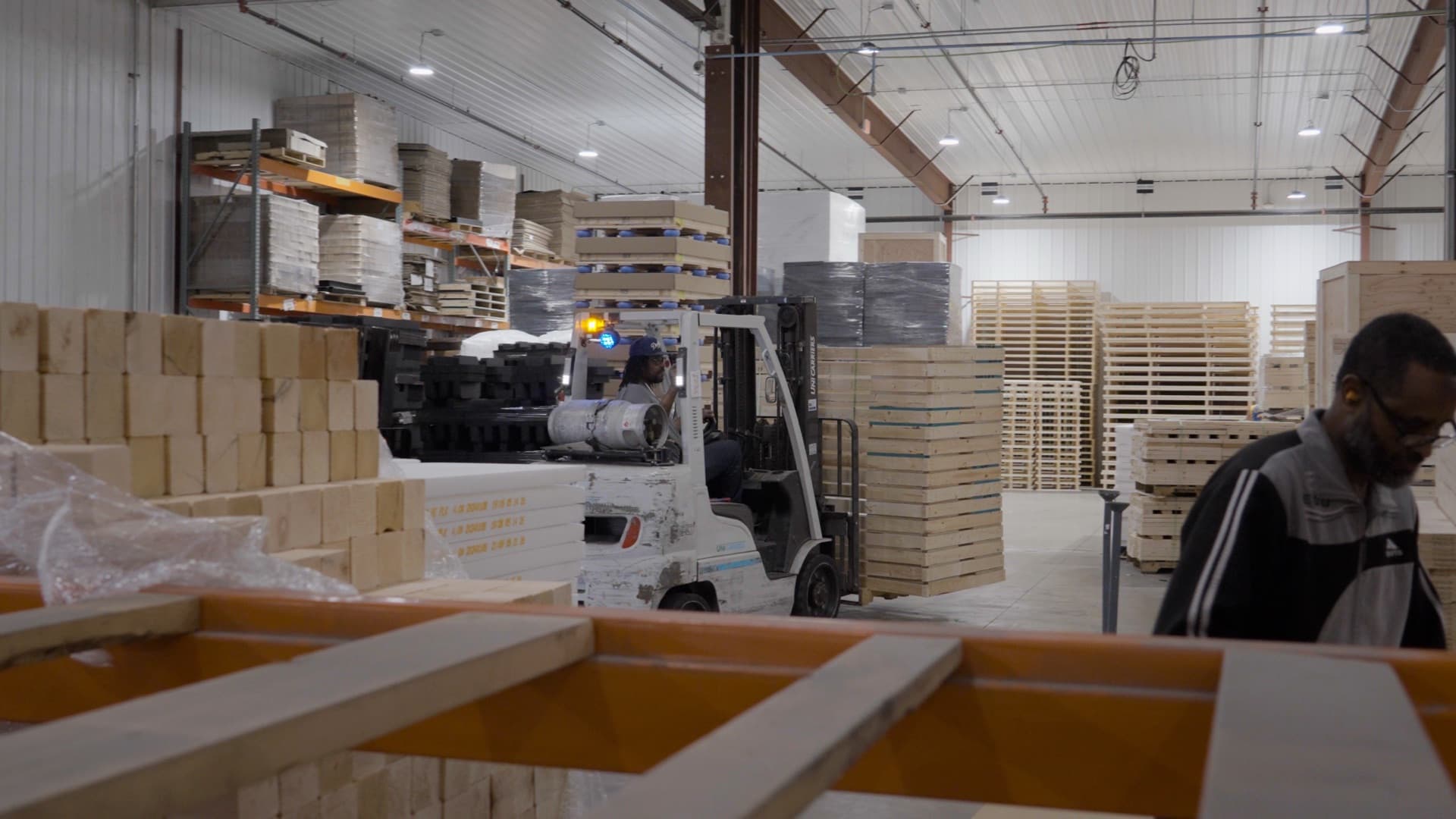 A forklift moving stacked wood crates through the FoamCraft warehouse